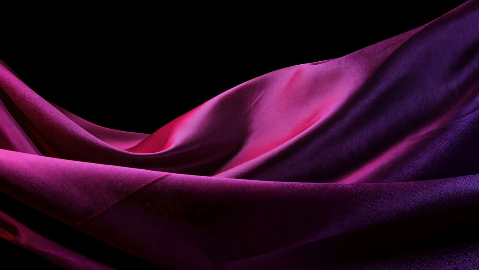 Deep plum silk billowing mid-air, its folds catching a neon-rose edge light
