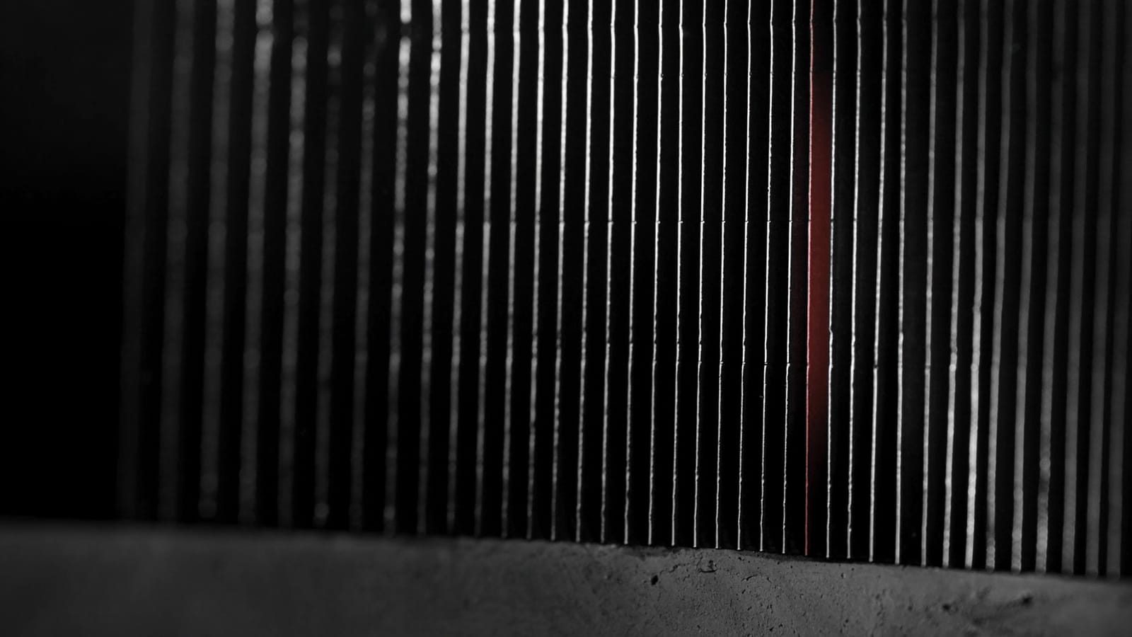 Thin lead sorts standing in a tight row, one of them red, caught in raking light