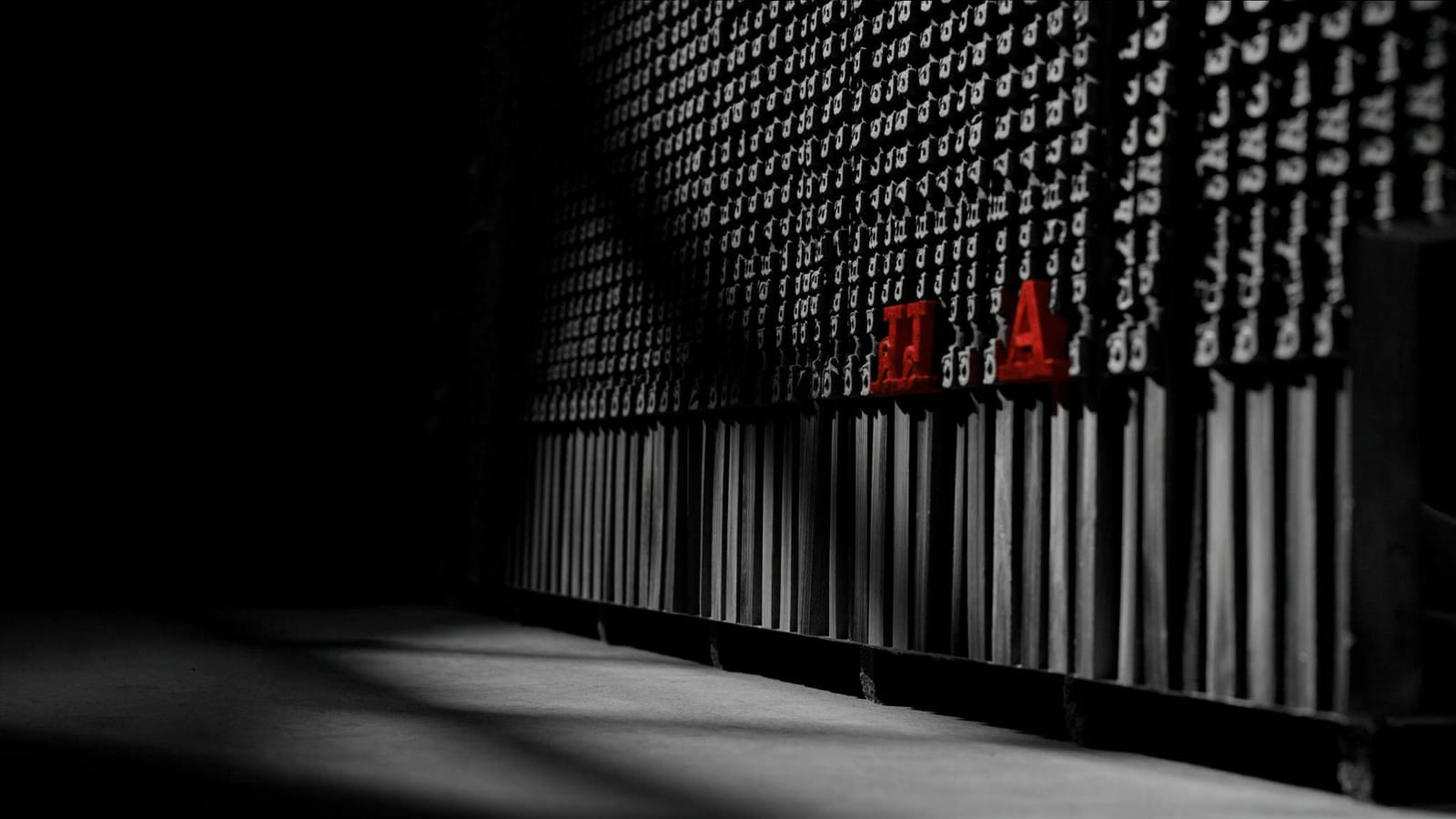 Rows of lead type in a dark case with two sorts, an A and an H, cast in red
